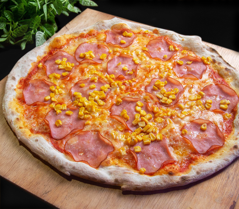 Hart an der Grenze Speisen Bild von einer Hart an der Grenze Hauspizza, die auf einem Holzbrettchen liegt, als Dekoration ein paar Blätter Vogerlsalat, alles auf schwarzem Hintergrund
