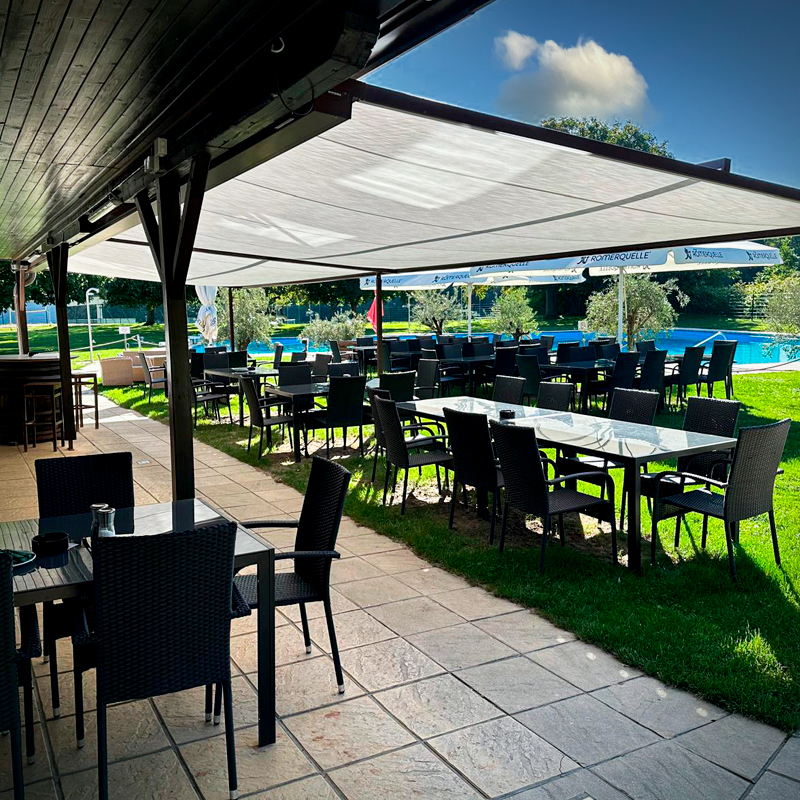 Blick in den einladenden Gastgarten. Ein breites Sonnensegel sorgt für eingenehm schattige Plätze.